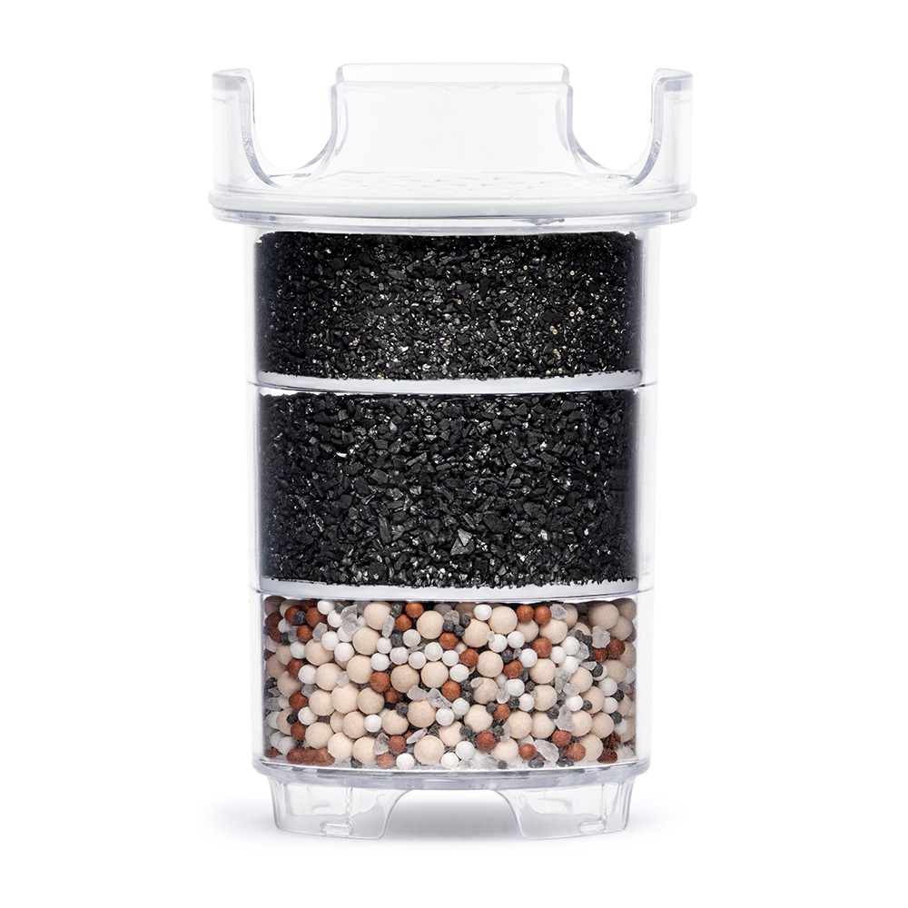 Eine transparente Wasserfilter-Kartusche mit sichtbaren Filter-Schichten aus Aktivkohle und Mineral-Keramiken, aufgenommen vor einem weißen Hintergrund.