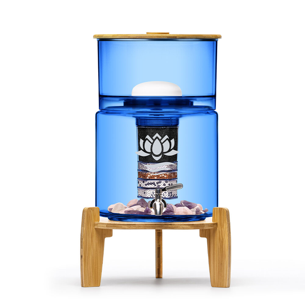 Eleganter Stand-Wasserfilter aus blauem Glas mit Bambus-Elementen, der die inneren Filterschichten und Edelsteine zeigt.
