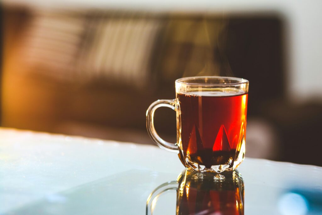 Eine dampfende Tasse mit frisch aufgebrühtem Tee steht auf einem Tisch und symbolisiert puren Teegenuss.